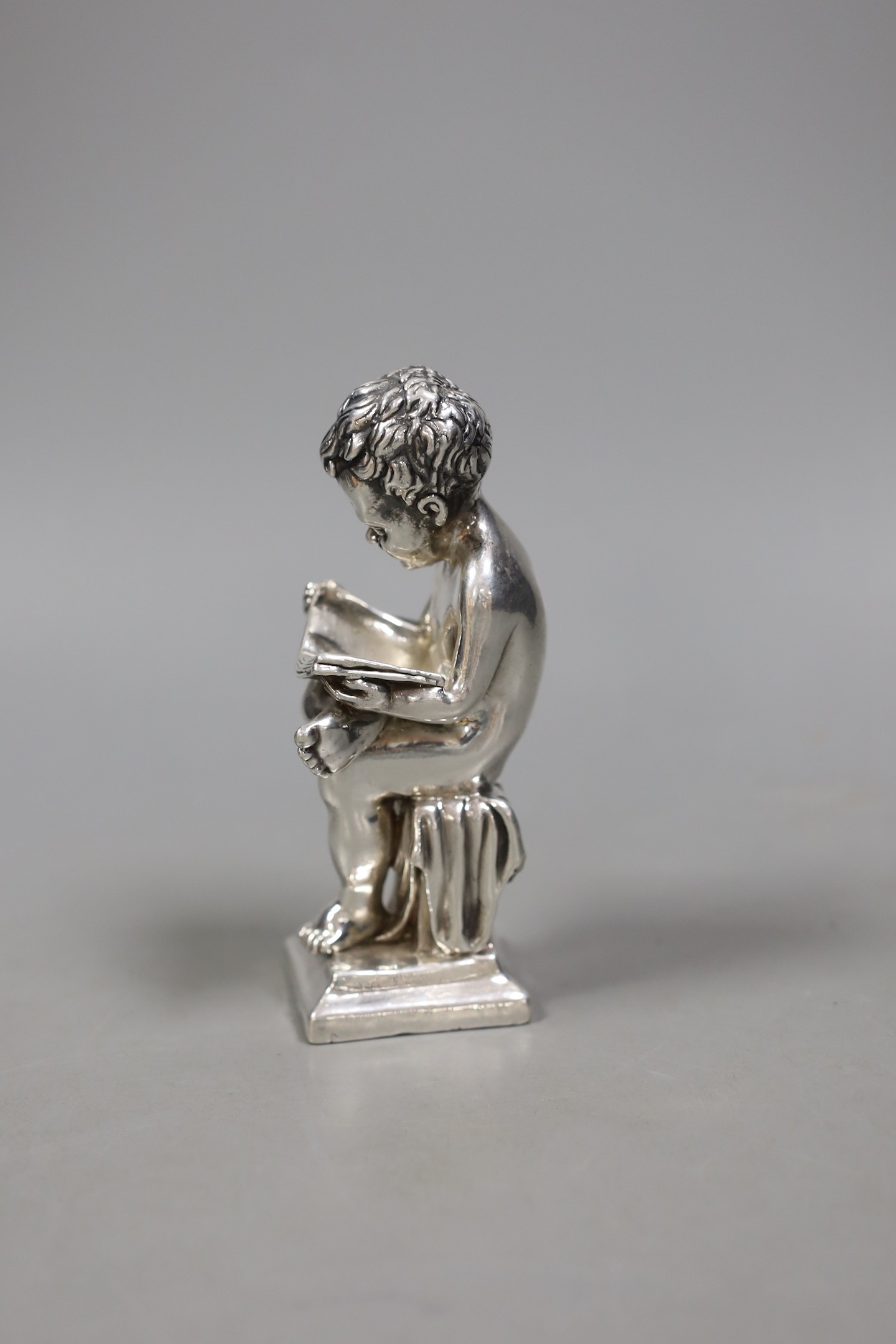 A modern Israeli sterling model of a seated young boy, reading, height 14.1cm.